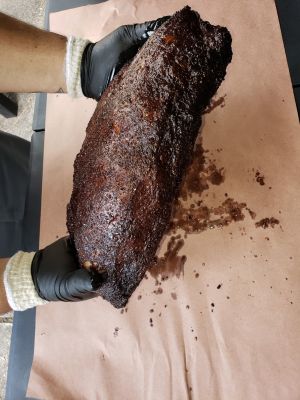 Close-up image of baked beans in a white bowl on a classic picnic table setting.
